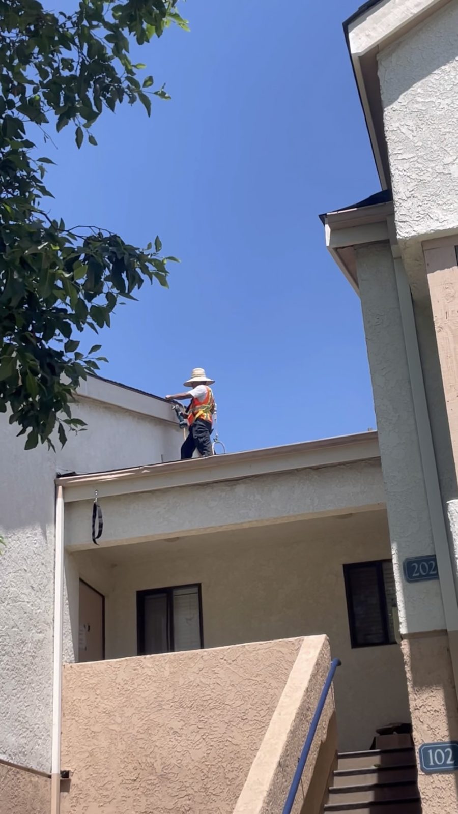 NRG Roofing crew member working along a roof parapet on a multifamily building in Ventura County