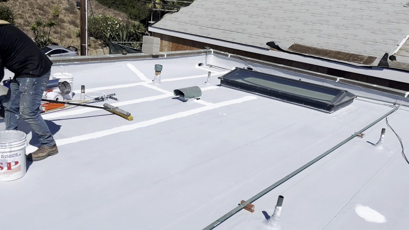 NRG Roofing crew rolling the seam coat on a Malibu flat roof restoration