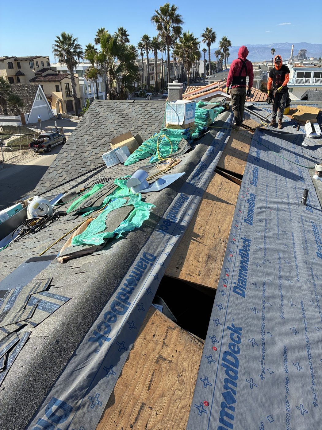 NRG Roofing crew installing architectural shingles with the ocean behind, Oxnard
