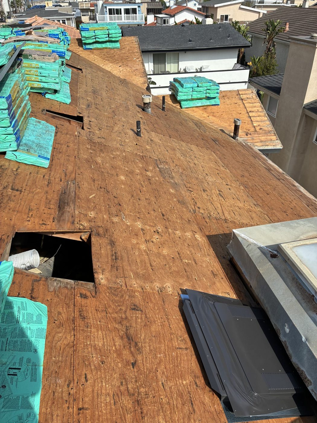 Roof deck exposed after tear-off, materials staged, Oxnard re-roof by NRG Roofing