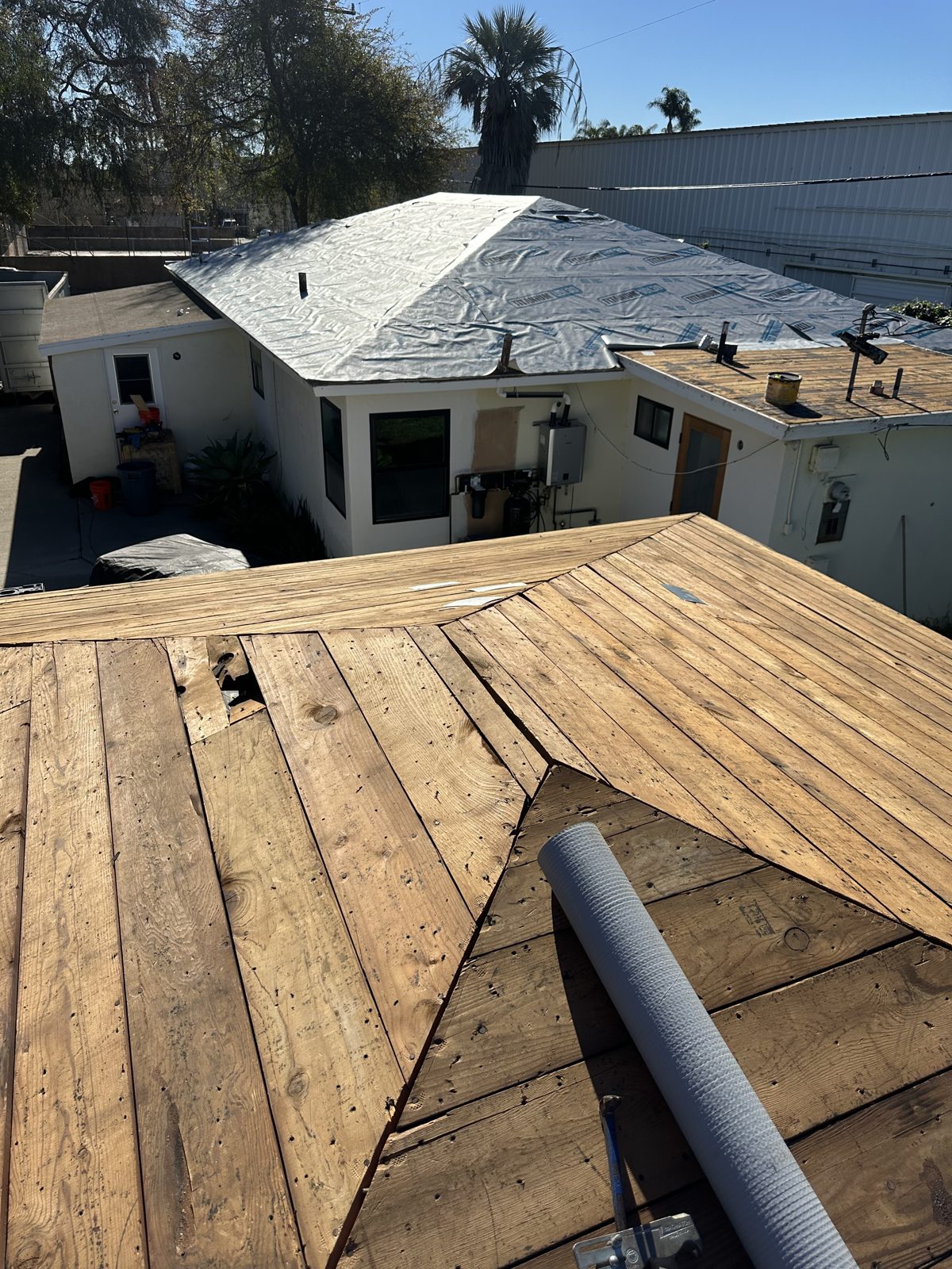 Roof tear-off to original plank deck with adjacent roof dried in with synthetic underlayment