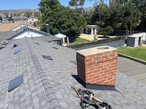New dimensional shingle roof with chimney flashing and skylight by NRG Roofing in Ventura