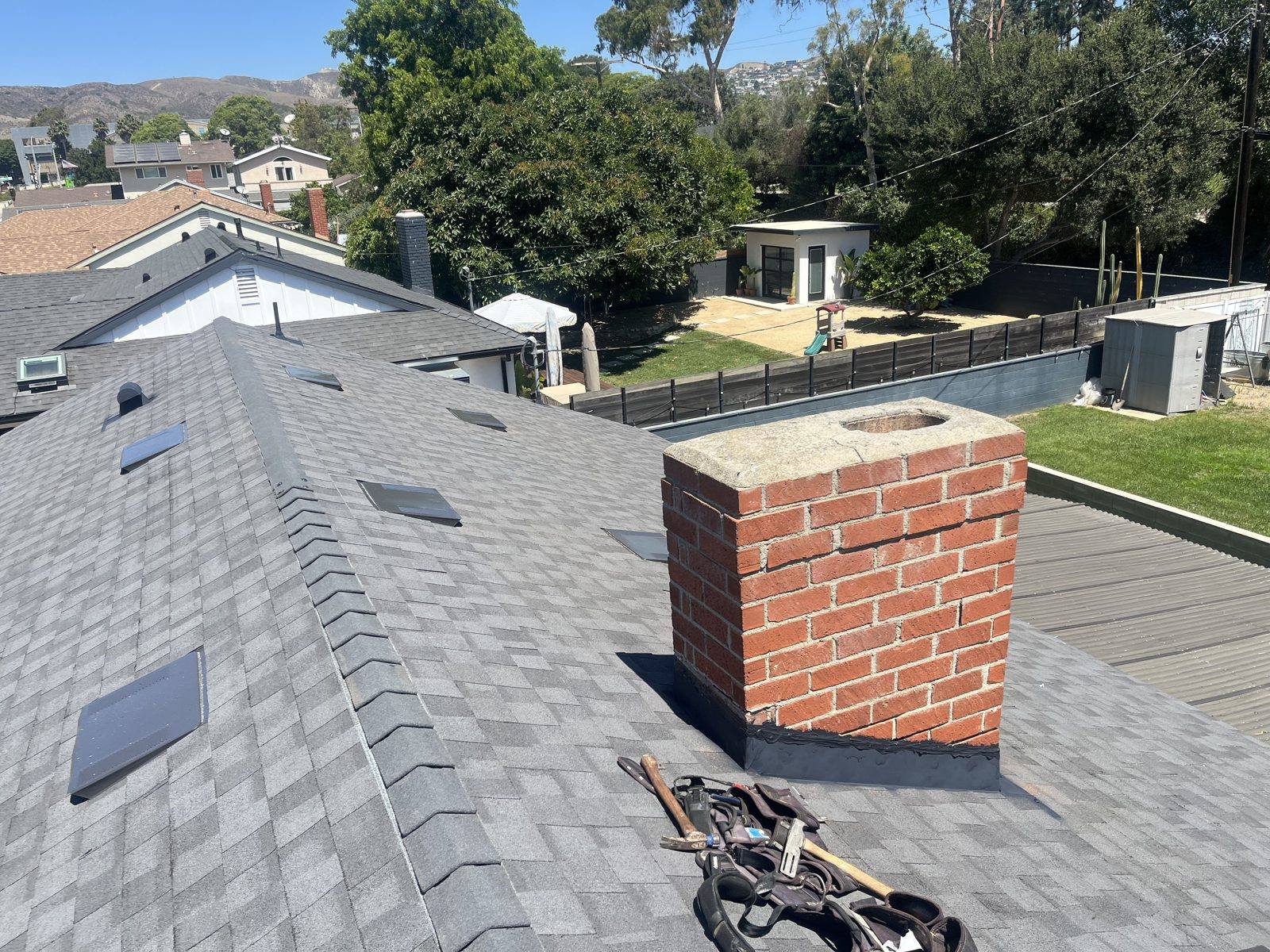 New dimensional shingle roof with chimney flashing and skylight by NRG Roofing in Ventura